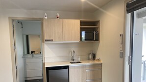 A compact kitchen with a dishwasher, a microwave, and a kettle. - MCM Motel (Christchurch)