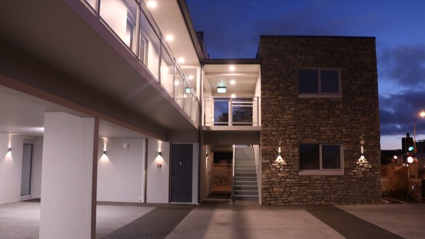 A modern building with a two-story structure, a stone facade, and a covered entrance with a staircase. - MCM Motel (Christchurch)