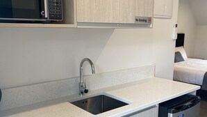 A modern kitchen with a microwave, sink, and dishwasher. - MCM Motel (Christchurch)