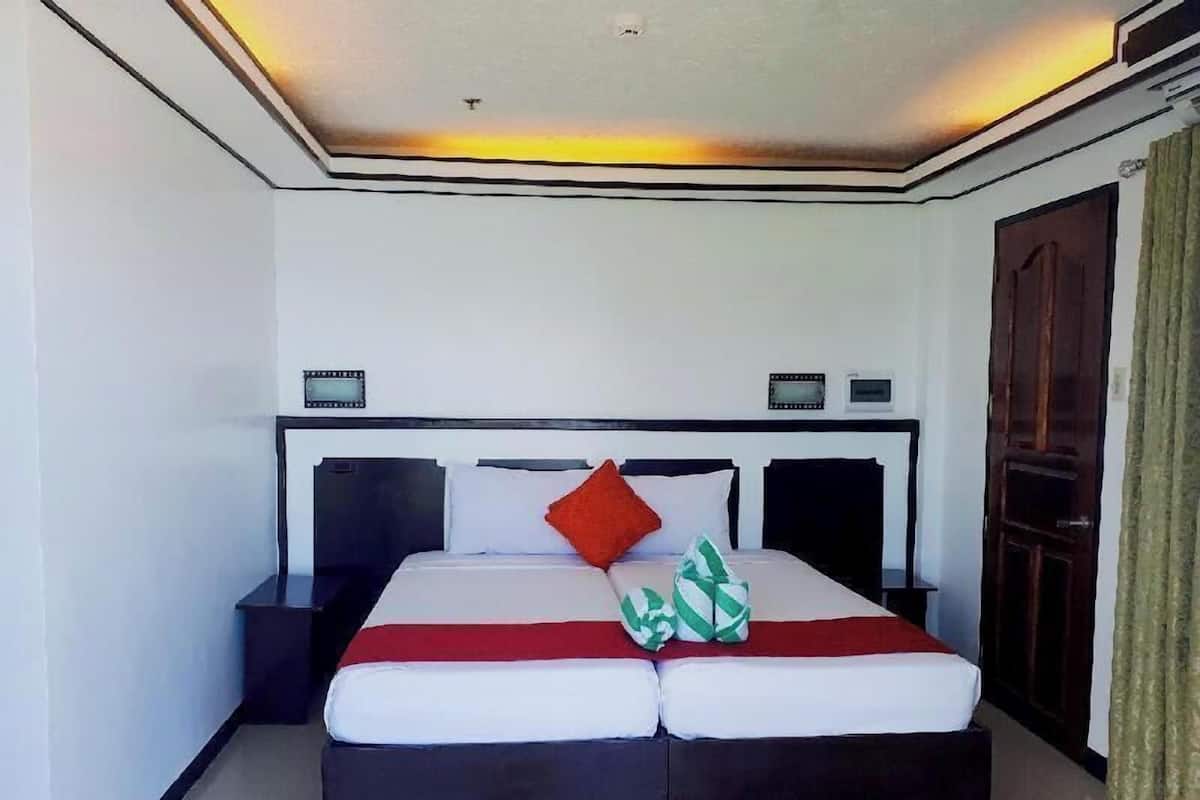 Ein Hotelzimmer mit Bett, Nachttischen, einer Uhr und einer Tür.