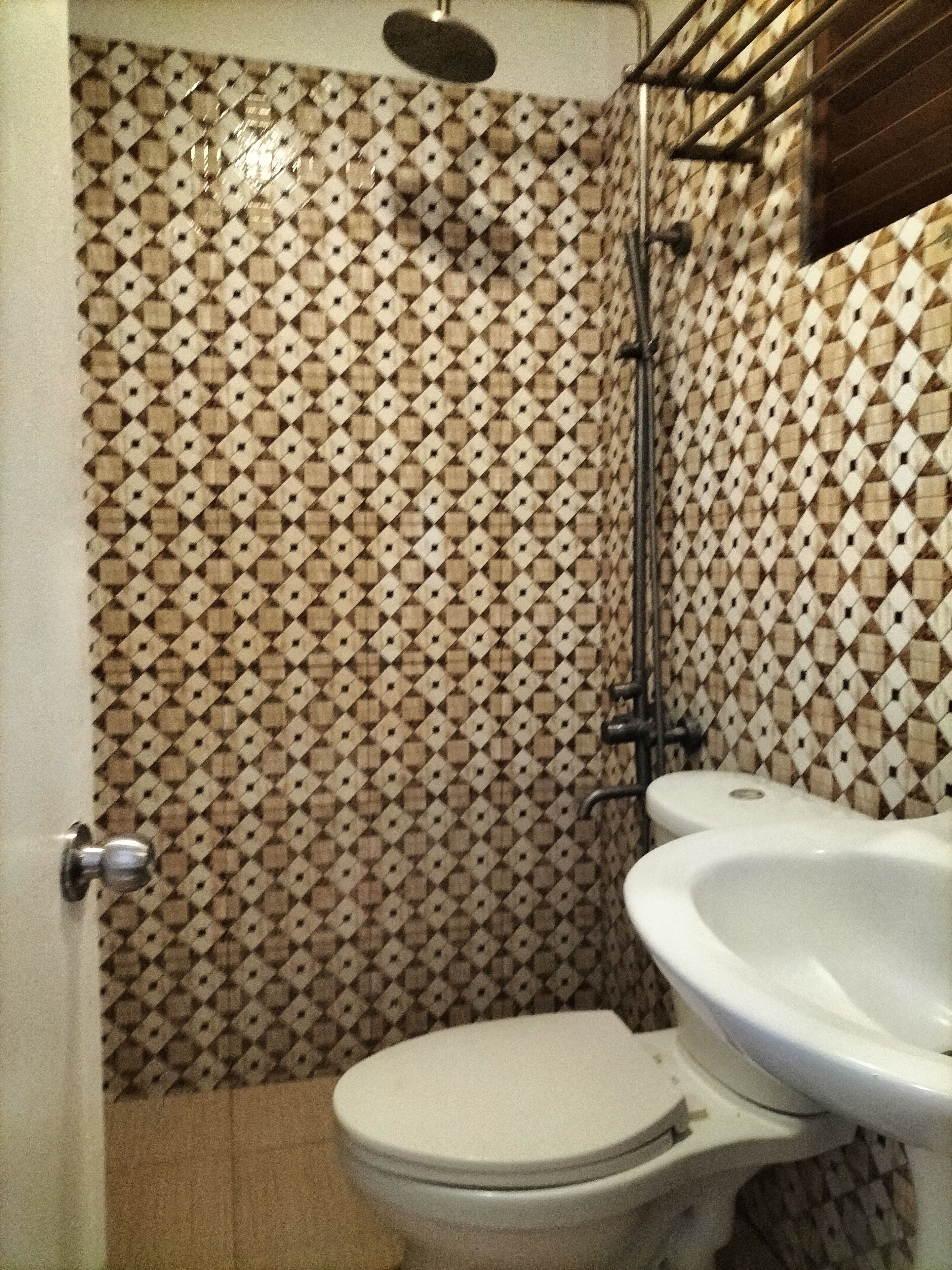 A bathroom with a patterned tile wall, a toilet, and a sink.