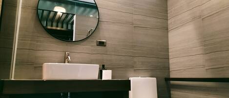 Un baño moderno con un espejo redondo, un lavabo y un inodoro.