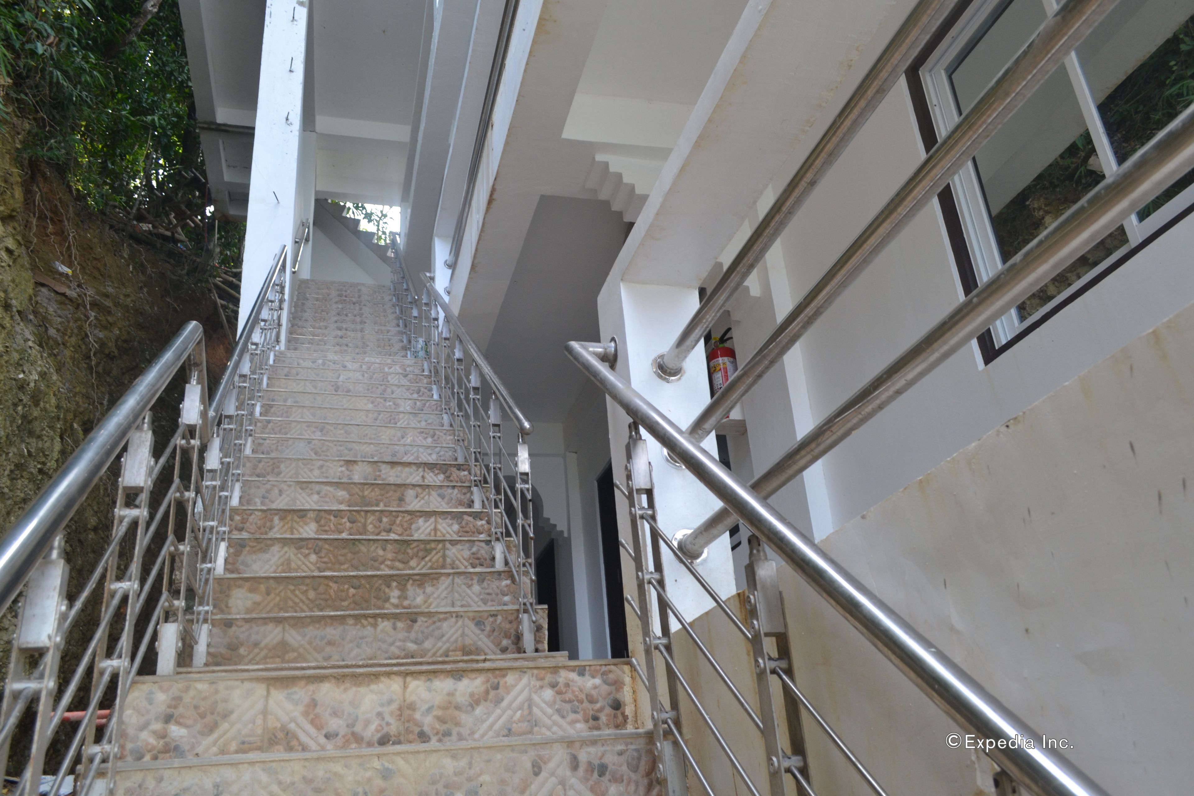 Una escalera con barandillas de metal y baldosas estampadas que sube a un piso superior.