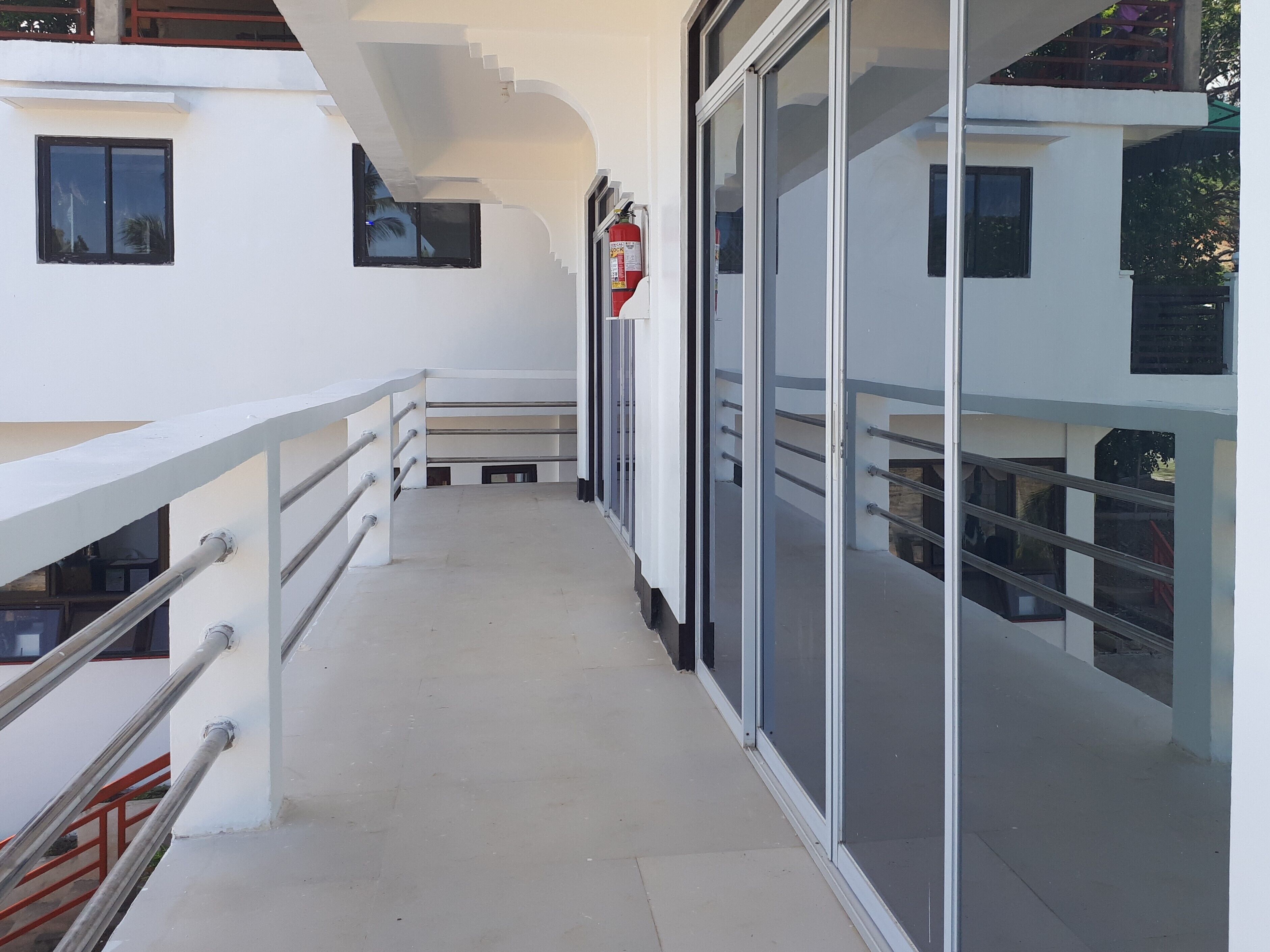 A modern building with a balcony, glass doors, and metal railings.