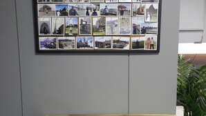 A wall with a collage of photos, a wooden table with two chairs, and a potted plant. - Philstay Myeongdong Metro (Seoul)
