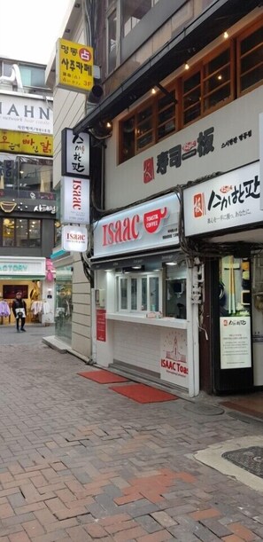 A street view with a coffee shop named 'Isaac Toast' and a clothing store.