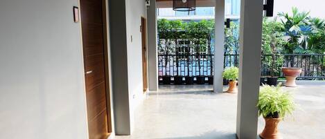 A corridor with a wooden door, a hanging light fixture, and potted plants.