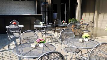 Un patio al aire libre con mesas y sillas de metal, algunas decoradas con flores.