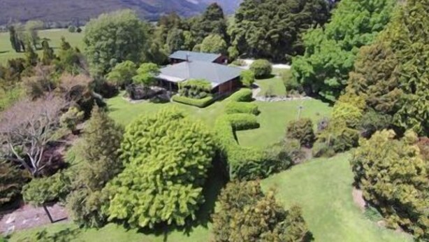 A large estate with a prominent house surrounded by well-maintained gardens and trees.