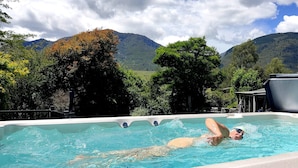 A person swimming in a pool with a mountainous landscape in the background.
