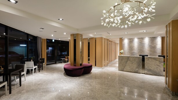 Eine moderne Lobby mit Marmorboden, einer Rezeption und einem einzigartigen Kronleuchter.