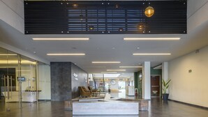 A spacious lobby with a reception desk, seating area, and a large potted plant.