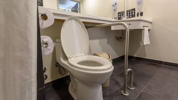 Un baño moderno con inodoro blanco, barra de apoyo y toallero.