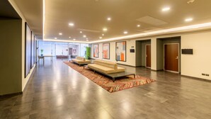 A spacious lobby with a long corridor, a sofa, and a patterned rug.