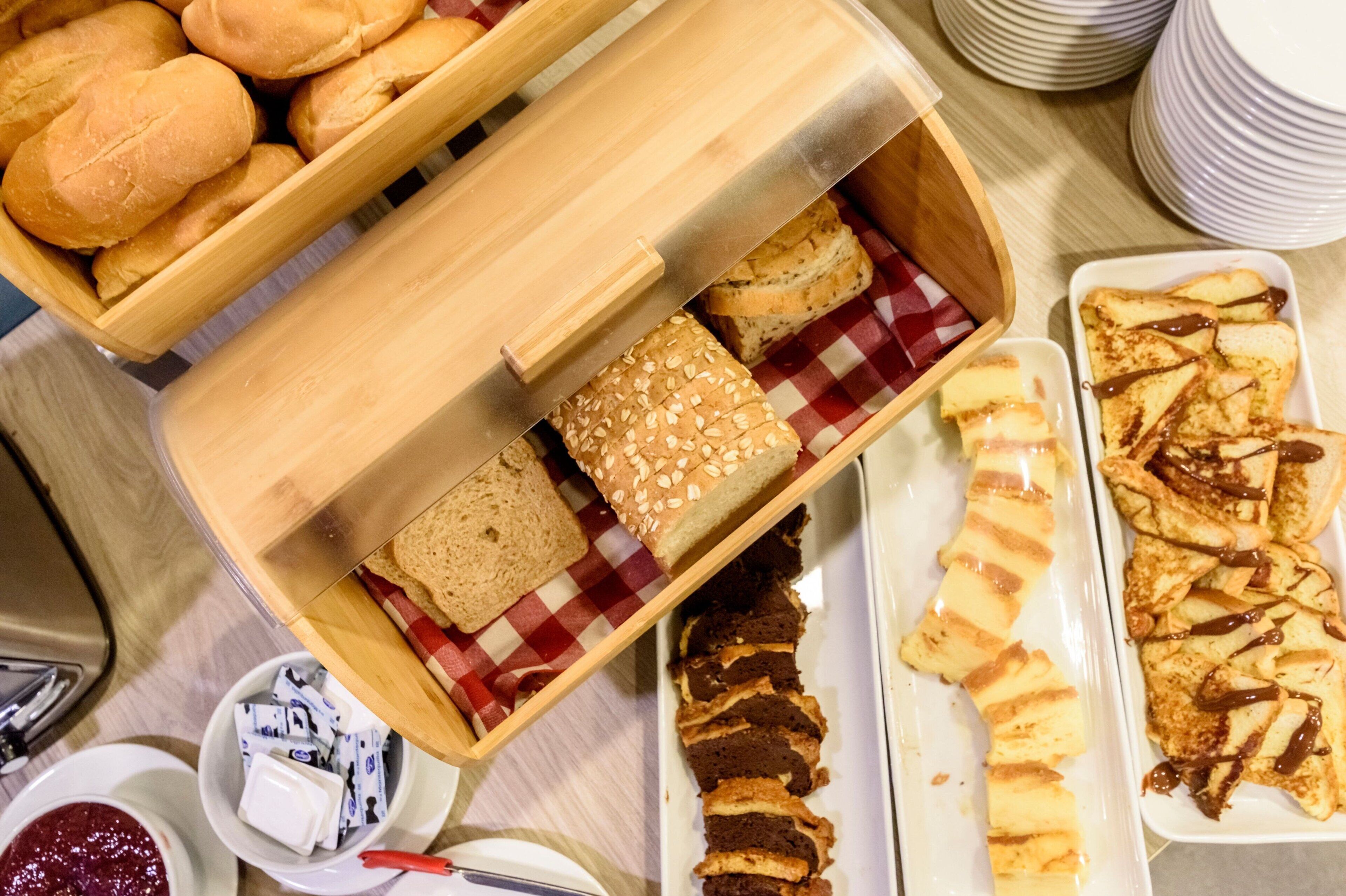 Une variété de produits de boulangerie, notamment du pain, des petits pains et des pâtisseries, présentés sur une table.