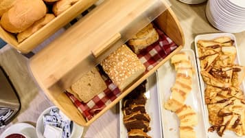 A variety of baked goods including bread, rolls, and pastries displayed on a table.