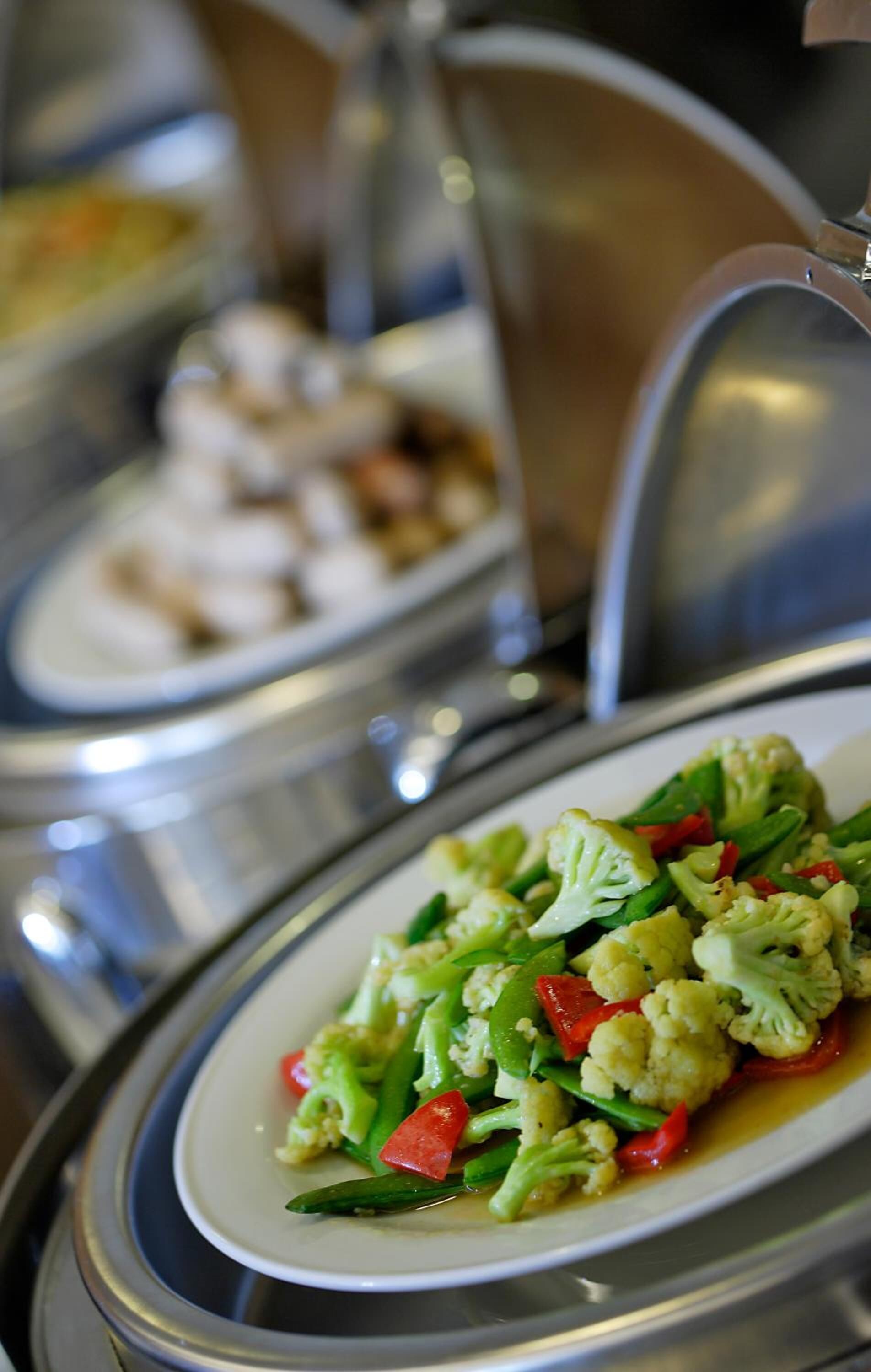A buffet with various dishes, including a plate of mixed vegetables.