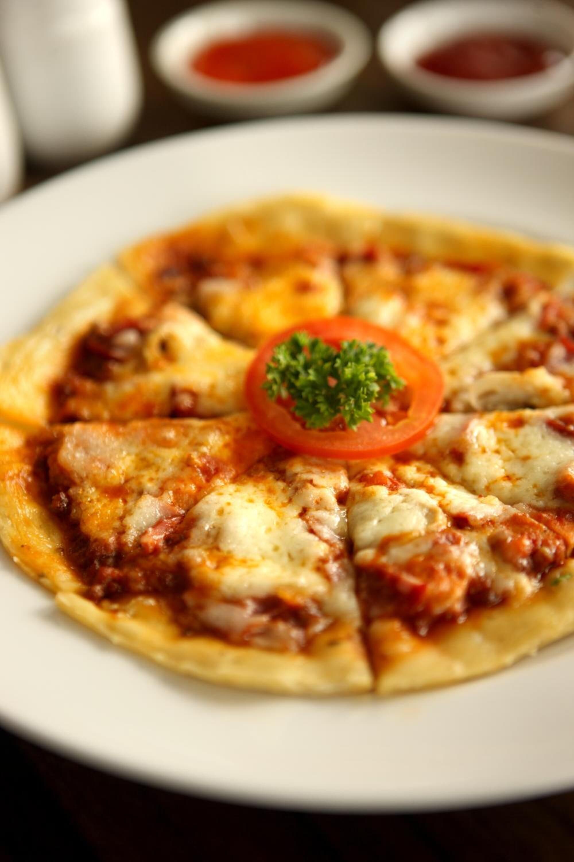 A pizza with cheese and tomato slices on a white plate.