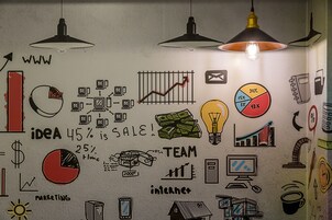 A wall with various business and marketing-related illustrations, including charts, graphs, and icons.