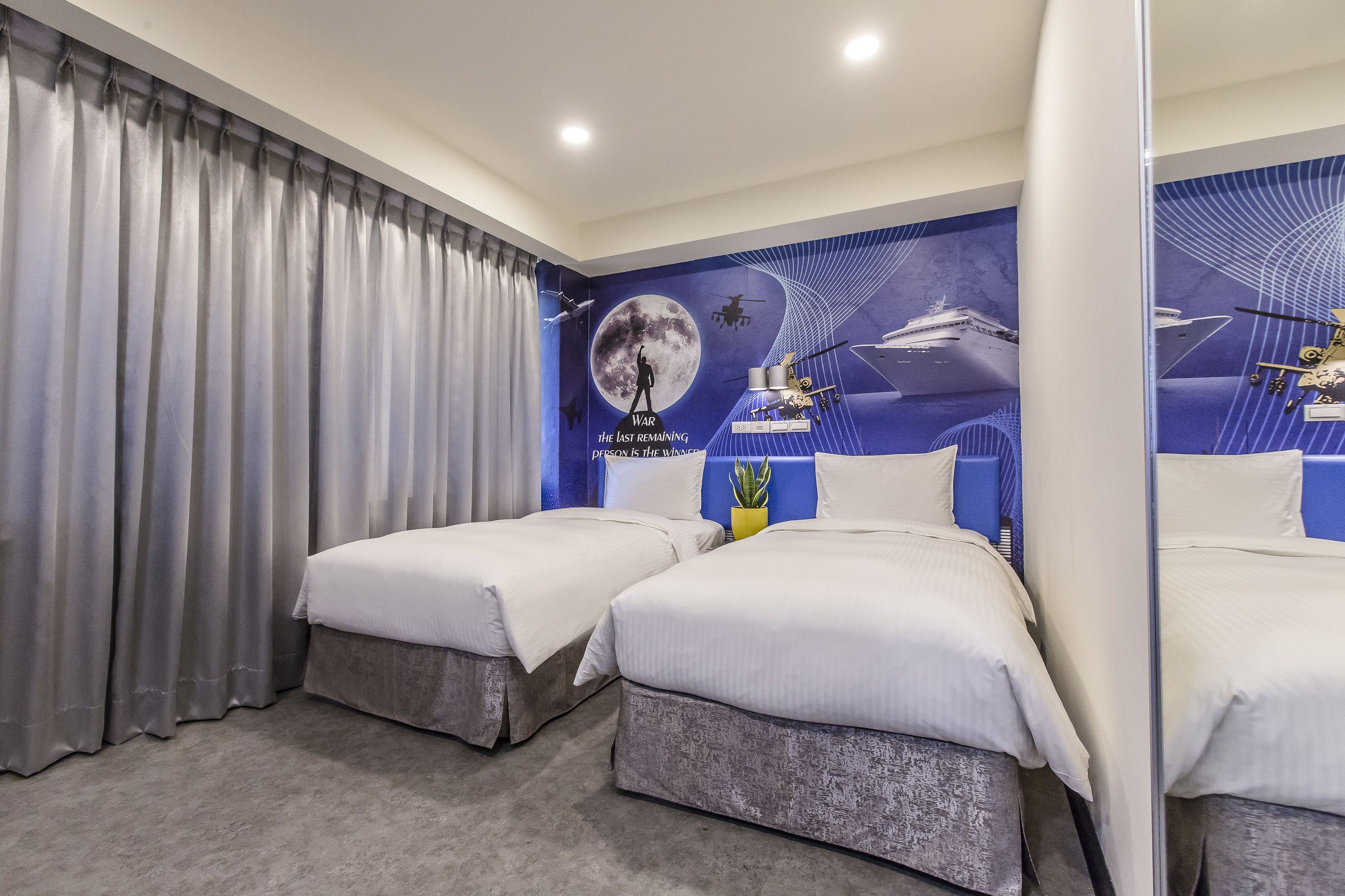 Hotellihuone, jossa on kaksi sänkyä, suuri ikkuna verhoilla, seinämaalaus ja peili.