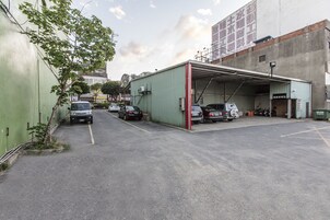 Un estacionamiento con varios coches y un edificio verde de techo rojo.