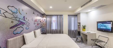 A modern hotel room with a large bed, a desk, a TV, and a mural on the wall.