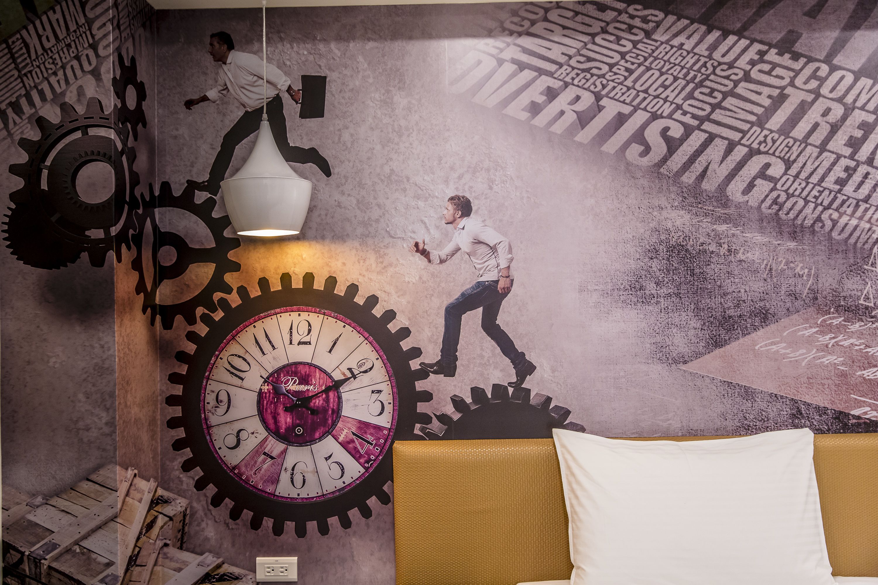 A room with a large wall clock, a sofa, and a wall with gears and silhouettes of people climbing.