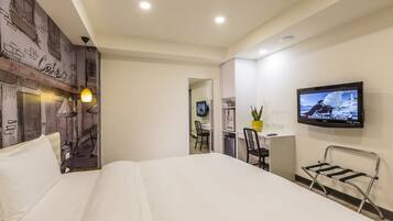 Una habitación de hotel con cama, escritorio, silla, televisor y un mural en la pared.
