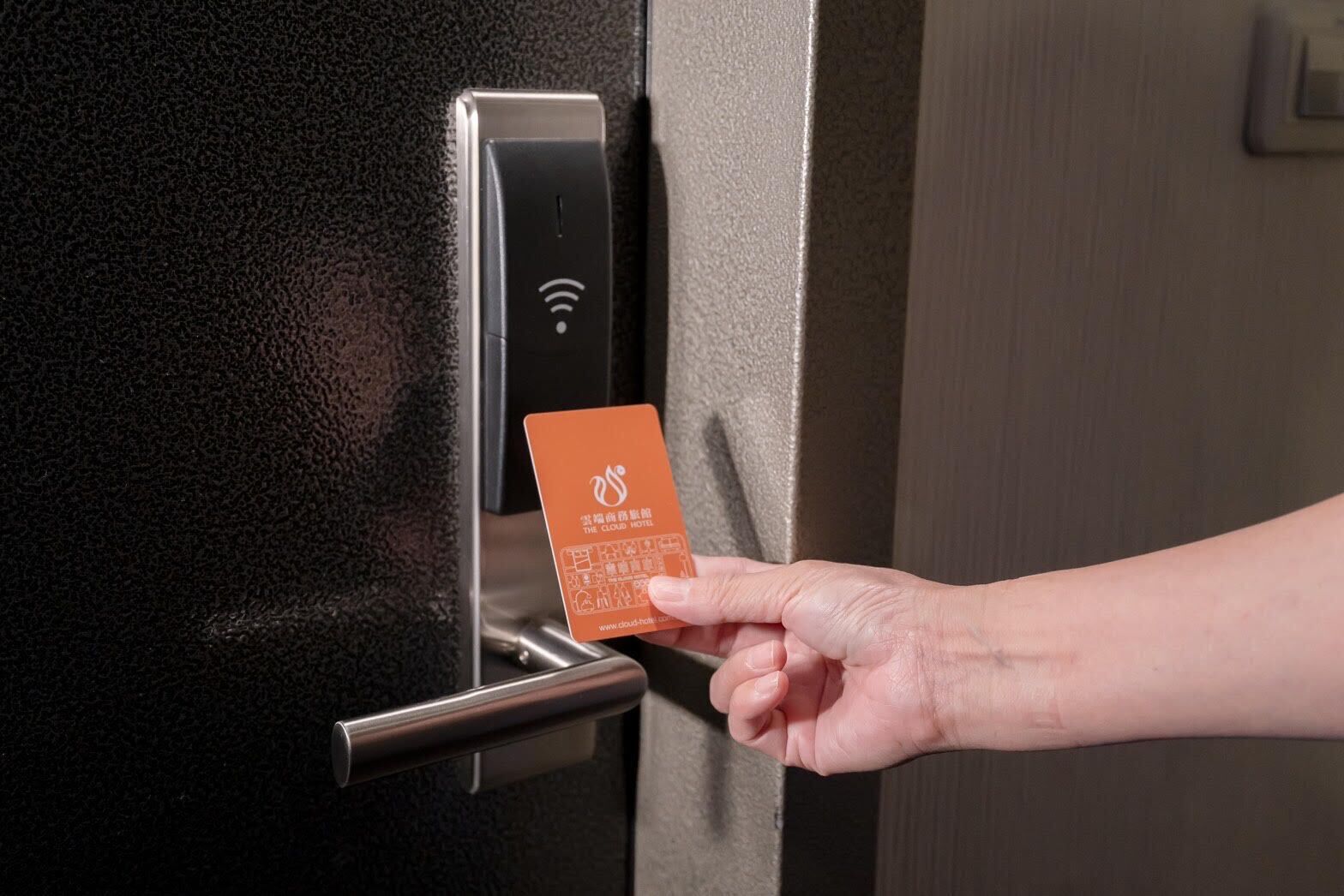 Eine Hand hält eine Hotelleiterkarte neben einer Tür mit einem Schlüsselschalter.