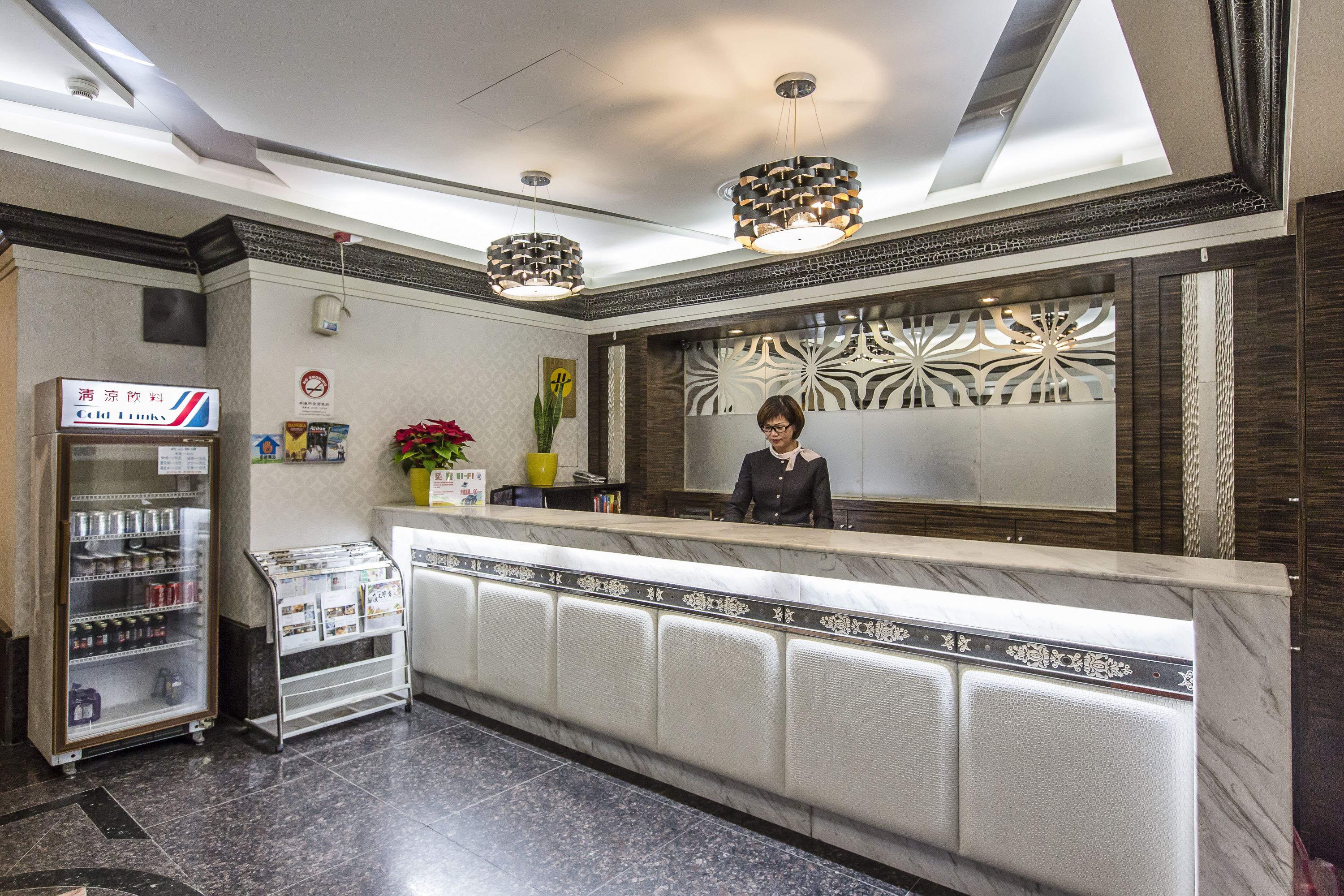 A hotel reception area with a marble counter, a vending machine, and a decorative wall.