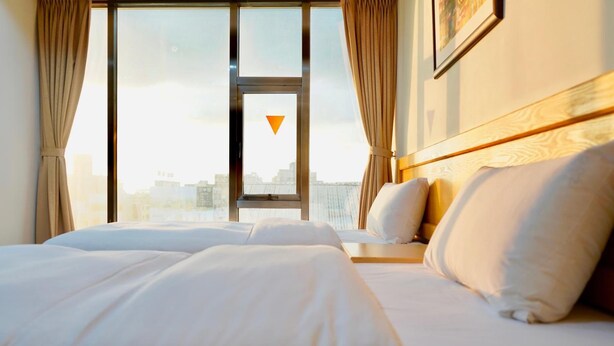 A hotel room with a large bed, a view of the city through a window, and a framed picture on the wall. - Fun House - Douliu Branch (Douliou)