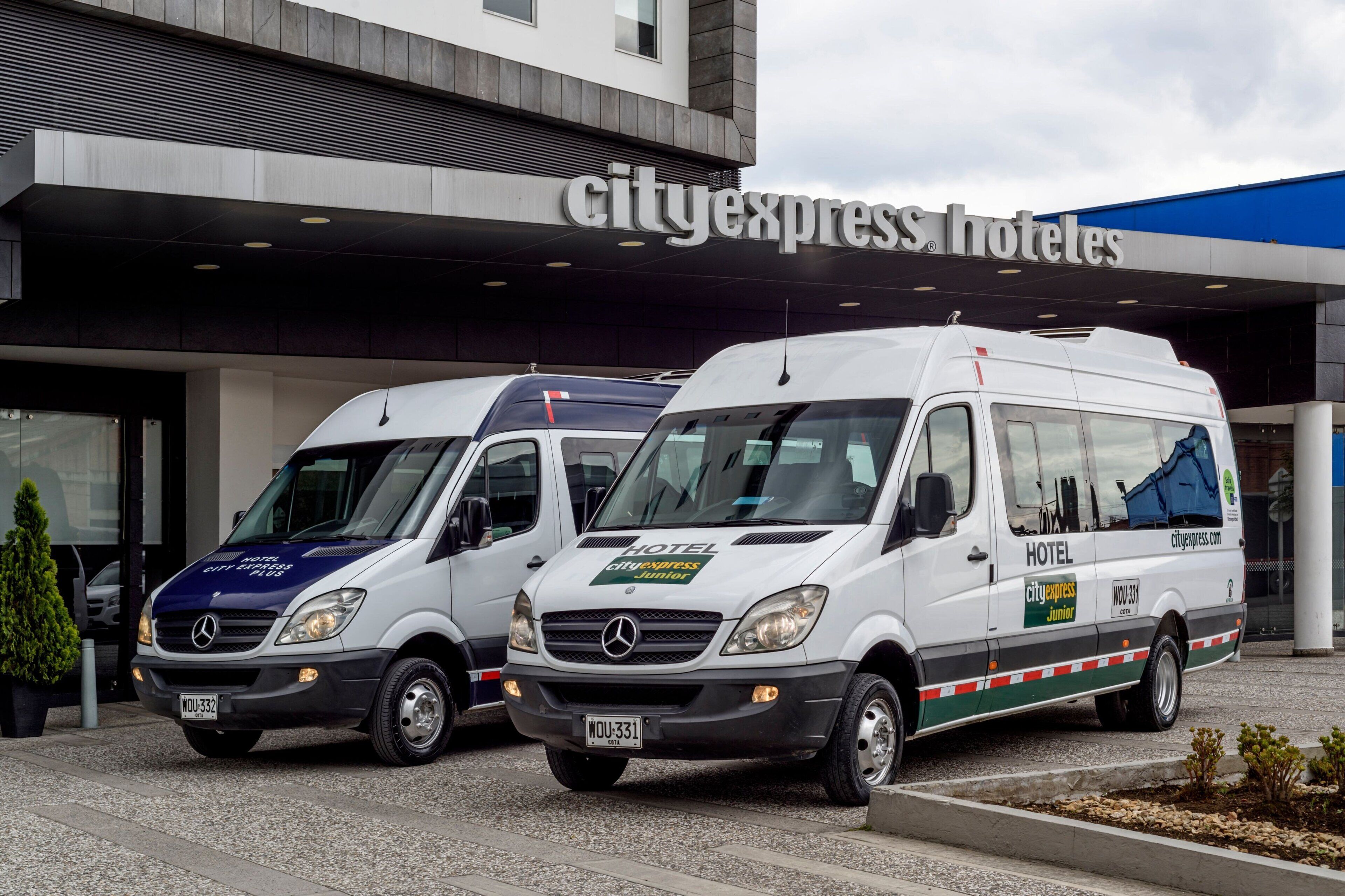 Two CityExpress Hotel service vans parked in front of the hotel entrance.