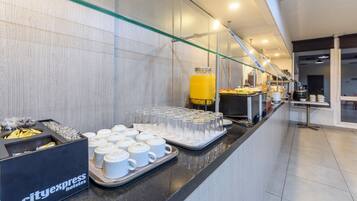 Un bufé de desayuno de hotel con diversas opciones de comida y un dispensador de jugo.