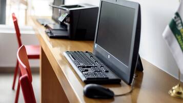 A wooden desk with a desktop computer, a keyboard, a mouse, and a printer.
