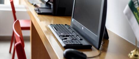A wooden desk with a desktop computer, a keyboard, a mouse, and a printer.