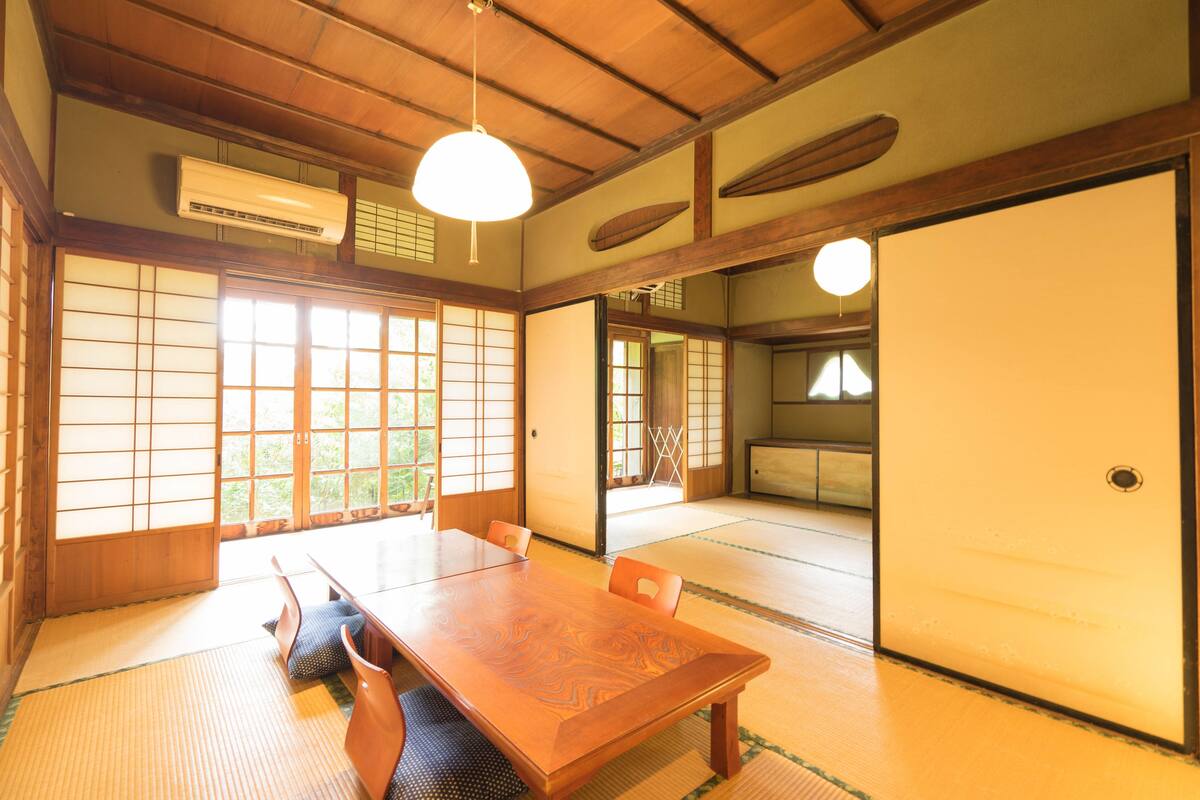 A traditional Japanese room with tatami flooring, a wooden table, and sliding doors.