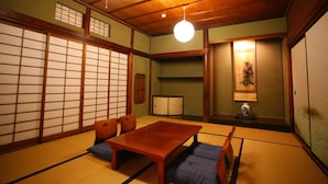Una habitación japonesa tradicional con suelo de tatami, una mesa de madera y cojines bajos.