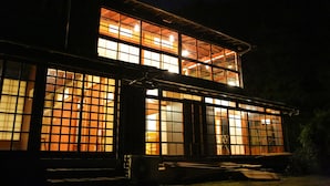 Un edificio de dos plantas con ventanas amplias y un balcón.