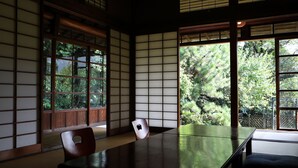 Una habitación japonesa tradicional con suelo de tatami, puertas correderas shoji y una mesa baja con una silla.