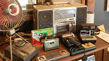 Eine Sammlung von Vintage-Audio-Geräten, darunter ein Sony FM-Stereokassettenrekorder, eine Polaroid-Kamera und ein Ventilator.