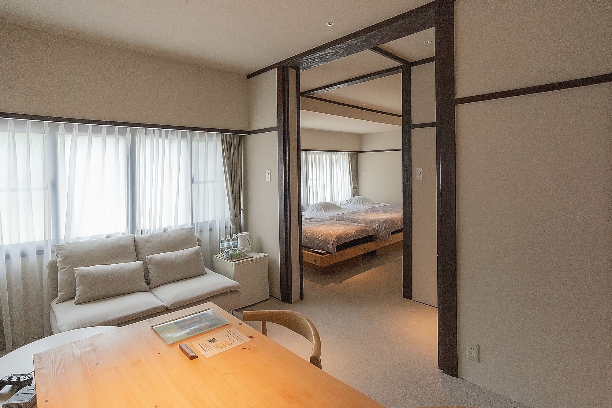 A room with a sofa, a wooden table, and a bed with a wooden frame.