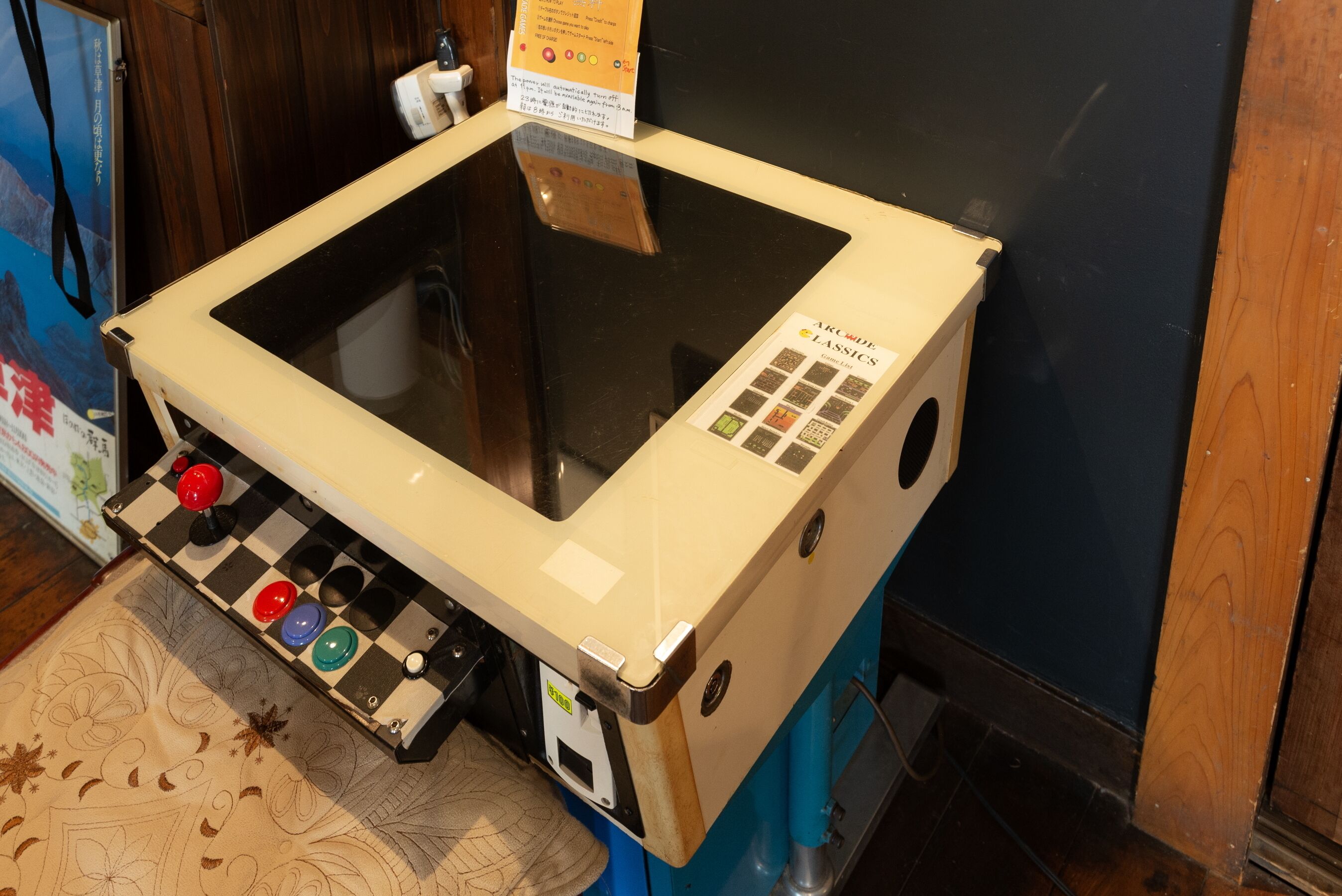 A room with a large glass table, a control panel with buttons, and a sign with Japanese text.