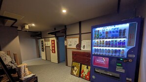 Màquina expenedora amb diverses opcions de begudes, un cartell de Wonda i una habitació japonesa tradicional amb portes corredisses i un petit santuari.