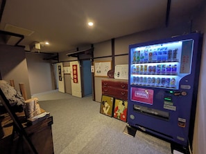 A vending machine with various drink options, a Wonda sign, and a traditional Japanese room with sliding doors and a small shrine. - Kusatsu Onsen Eidaya (Kusatsu)