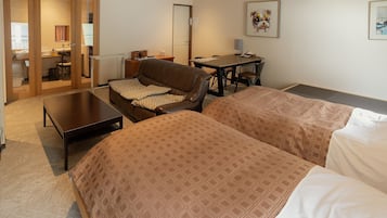 A hotel room with two beds, a sofa, a desk, and a chair.