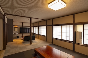 A traditional Japanese room with tatami flooring, a wooden table, a television, and sliding doors. - Kusatsu Onsen Eidaya (Kusatsu)