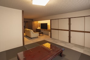 A hotel room with a large wardrobe, a sofa, a television, and a small table. - Kusatsu Onsen Eidaya (Kusatsu)