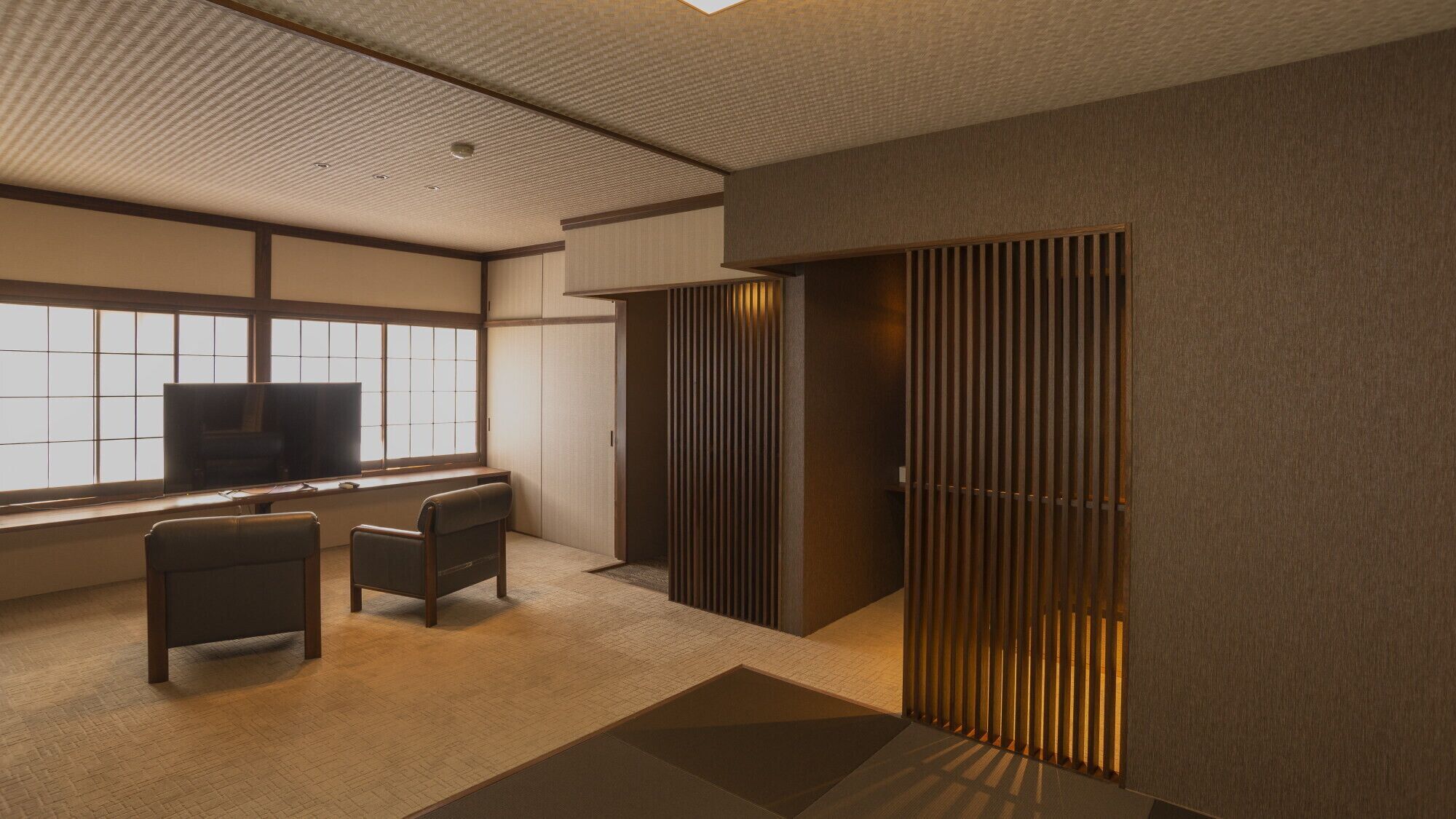 A modern room with a desk, two chairs, a television, and a sliding door.