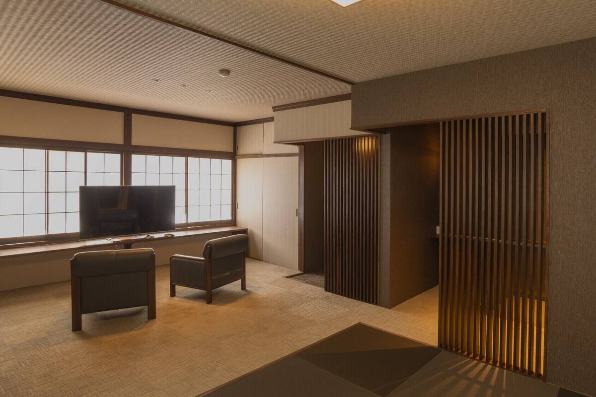 A modern room with a desk, two chairs, a television, and a sliding door.