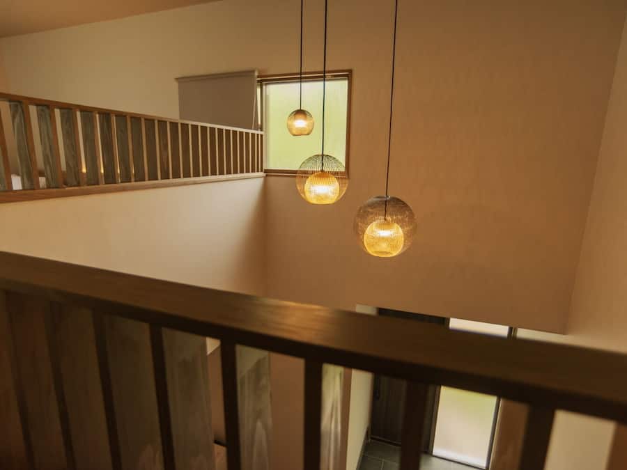 Uma escada com corrimão de madeira e duas luminárias esféricas penduradas.
